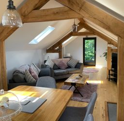 An attic living space with wooden beams sofas a coffee table TV and a dining table at Lugg View in Cross Keys near Hereford
