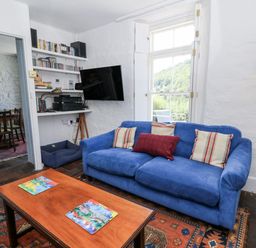 A living room with a blue sofa and a coffee table at Dolwylan Cottage in Cwmtydu near New Quay