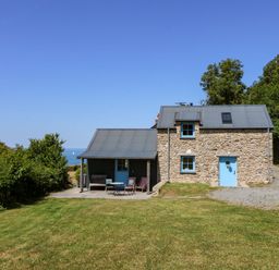 A house with a blue door and patio furniture at Dolwylan Barn Cwmtydu near New Quay