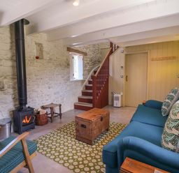 A living room with a stove and sofa at Dolwylan Barn in Cwmtydu near New Quay