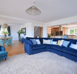A living room with blue sofas and a dining area with blue chairs at Ty Ni in New Quay