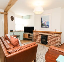 A living room with leather sofas a brick fireplace and a television at The Yellow House 13 King Street Dawlish