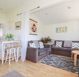 A living room with two gray sofas a rug a coffee table and a small dining table with stools at 224 Atlantic Bays in St Merryn