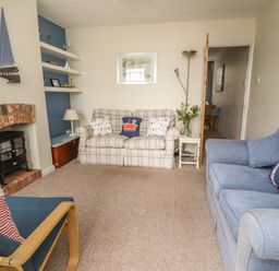 A living room with two sofas armchair fireplace and bookshelves at 9 Harefield Cottages in Lympstone