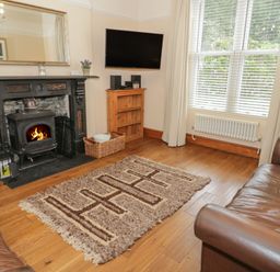 A living room with a fireplace television on a wooden shelf and two leather sofas at Ty Capel in Betws-Y-Coed