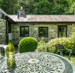 A table and chairs with wine and glasses at Tyn Y Ffynnon in Betws-Y-Coed