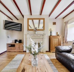 A living room with a television, fireplace, and wooden furniture at Tyn Y Ffynnon in Betws-Y-Coed