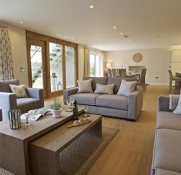 An open living and dining area with sofas armchairs coffee tables dining table and kitchen at 3 The Drive Hillfield Village Dartmouth