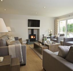 A living room with gray sofas a wood burning stove and a TV mounted on the wall at 3 The Drive Hillfield Village Dartmouth