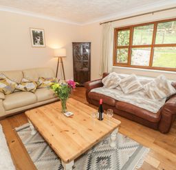 A living room with two sofas a wooden coffee table with flowers and wine in Bryn Elsi in Betws-Y-Coed