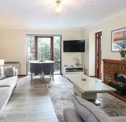 A living room with sofas a coffee table a dining table with chairs a wall-mounted television and a fireplace at Seaview Cottage in Salthouse Norfolk