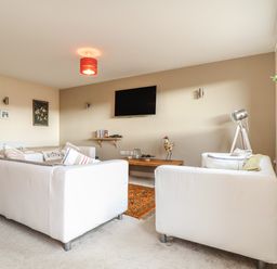 A living room with white sofas a wall-mounted television and a wooden coffee table at Maple in Falmouth
