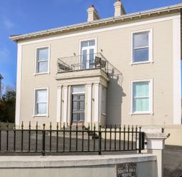 A beige two-story house with black door and balcony above the entrance at Sea Breeze in Ballycastle