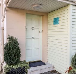 A house entrance with a pale green door and potted plants on either side at Sea Breeze in Ballycastle