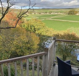 A balcony with a table and chair overlooking a landscape at The Sett on the Wharfe in Skipton