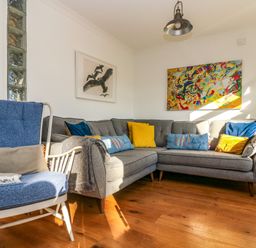 A living room with a grey sectional sofa with cushions and a blue armchair with a cushion and blanket