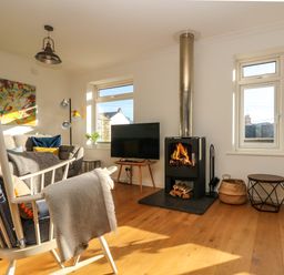 A living room with a fireplace a television a rocking chair and a sofa at Rock Pool House in Porthleven