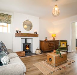 A living room with a fireplace wooden chest coffee table sofa and wooden cabinet at Plas Coch Rhoscolyn in Rhoscolyn