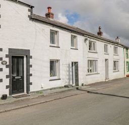 A row of terraced houses with white walls and black and green door and window frames on a street