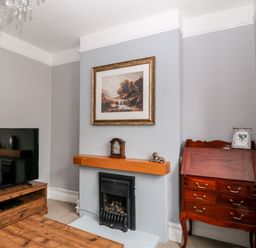 A living room with a fireplace wooden TV stand and a wooden cabinet at Daisy Cottage in Bideford