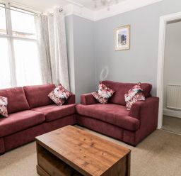 A living room with two red sofas and a wooden coffee table at Daisy Cottage in Bideford