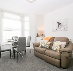 A living room with a sofa and dining table at 76A Mackworth Road in Porthcawl
