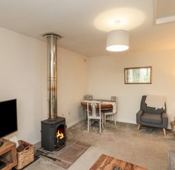 A living room with a wood stove and a dining table with chairs at Chestnut Cottage in Filey
