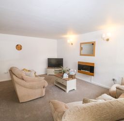 A living room with sofas coffee table tv and wall mirror at Rose Cottage in Marldon