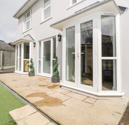 The exterior of a white two-story house with large glass doors and windows on a stone patio at Fonthill in Torquay