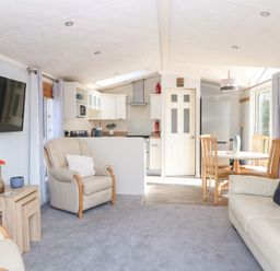 A living room with armchairs a sofa television and a small dining area with table and chairs at 109 Pentney Lakes Pentney near King's Lynn