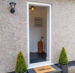 An open front door showing an entrance with an umbrella stand and two framed pictures at The Old Vicarage Retreat Luxulyan