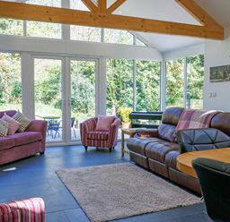 A living room with sofas armchairs a dining table and large windows at The Old Vicarage Retreat Luxulyan