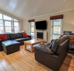 A living room with two black leather sofas a wooden coffee table and a wall mounted tv at Oakwood Lodge in Langdale 3 White Cross Bay Windermere
