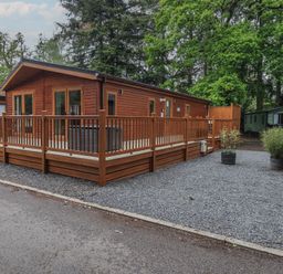 A wooden lodge with decking and gravel area at Ridgway Lodge Calgarth 40 White Cross Bay near Windermere