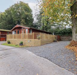 An outdoor area with a lodge and decking at Buttermere Lodge near Glade 5, Fallbarrow Park near Bowness on Windermere
