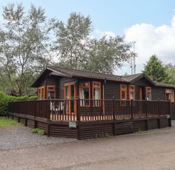A lodge with a deck surrounded by trees at Rydal Lodge in Grasmere 24, White Cross Bay near Windermere