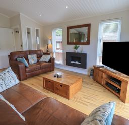 A living room with brown leather sofas wooden coffee table and TV unit at Wansfell Retreat Lodge Wansfell 4 Limefitt Park near Windermere