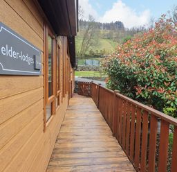 A wooden pathway leading to a lodge with a sign at Elder Lodge Kirkstone 5 Limefitt Park near Windermere