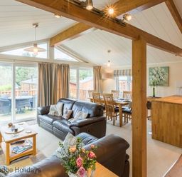 A living area with leather sofas a wooden coffee table and dining table near a kitchen island at Sheffield Pike Lodge Ullswater 8 Limefitt Park near Windermere