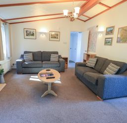A living room with two sofas a round wooden coffee table and a fireplace at Walkers Retreat Lodge Fellside 5 Limefitt Park near Windermere