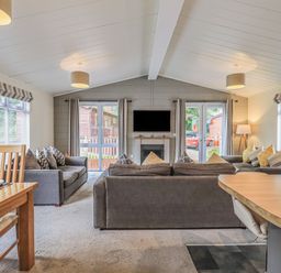 A living room with sofas and a TV above a fireplace at Daffodils Lodge Oakside 7 Fallbarrow Park in Bowness on Windermere