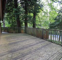 A wooden deck with railing outside a house surrounded by trees at Forest Pines Lodge Beech Hill 10 Fallbarrow Park near Bowness on Windermere