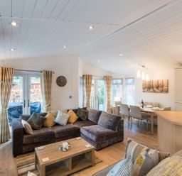 A living room with sofas a coffee table and a dining area with a table and chairs at Broad Larch Lodge in Glade 16 Fallbarrow Park near Bowness on Windermere