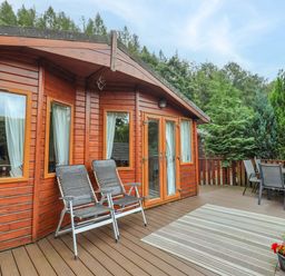 An outdoor area with a wooden lodge and seating at Birthwaite Lodge Fellside 6 Limefitt Park near Windermere