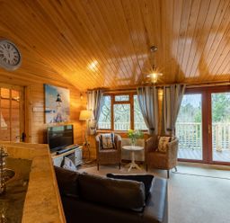A living room with wicker chairs and a small table near windows and glass doors at Lakeshaven Skiptory Howe 16 White Cross Bay near Windermere