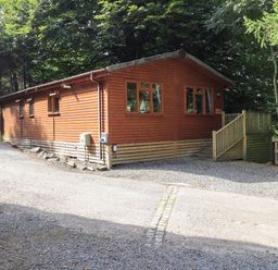 A wooden cabin with windows and a small staircase surrounded by trees at Lakeshaven Skiptory Howe 16 White Cross Bay near Windermere