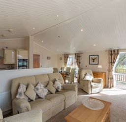 A living room with beige sofas and a wooden coffee table with a clear bowl at Waterbird Lakeview 4 White Cross Bay near Windermere