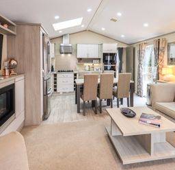 An open living room and kitchen with a dining table six chairs a sofa and a fireplace at Glenridding Lodge Grasmere 2 White Cross Bay near Windermere