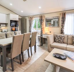 A dining area with a table and six chairs next to a kitchen and a living room with a sofa and coffee table at Glenridding Lodge Grasmere 2 White Cross Bay near Windermere