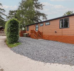 A lodge with a gravel area and steps at Beech Grove Lodge, Glade 17, Fallbarrow Park near Bowness on Windermere